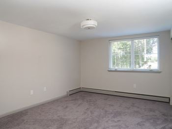 An empty living room with a window and carpet
